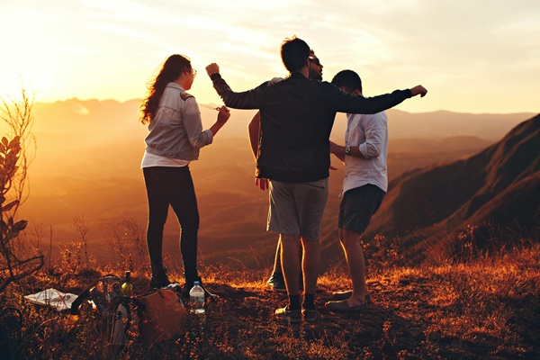 group of four friends celebrating on top of a hill
